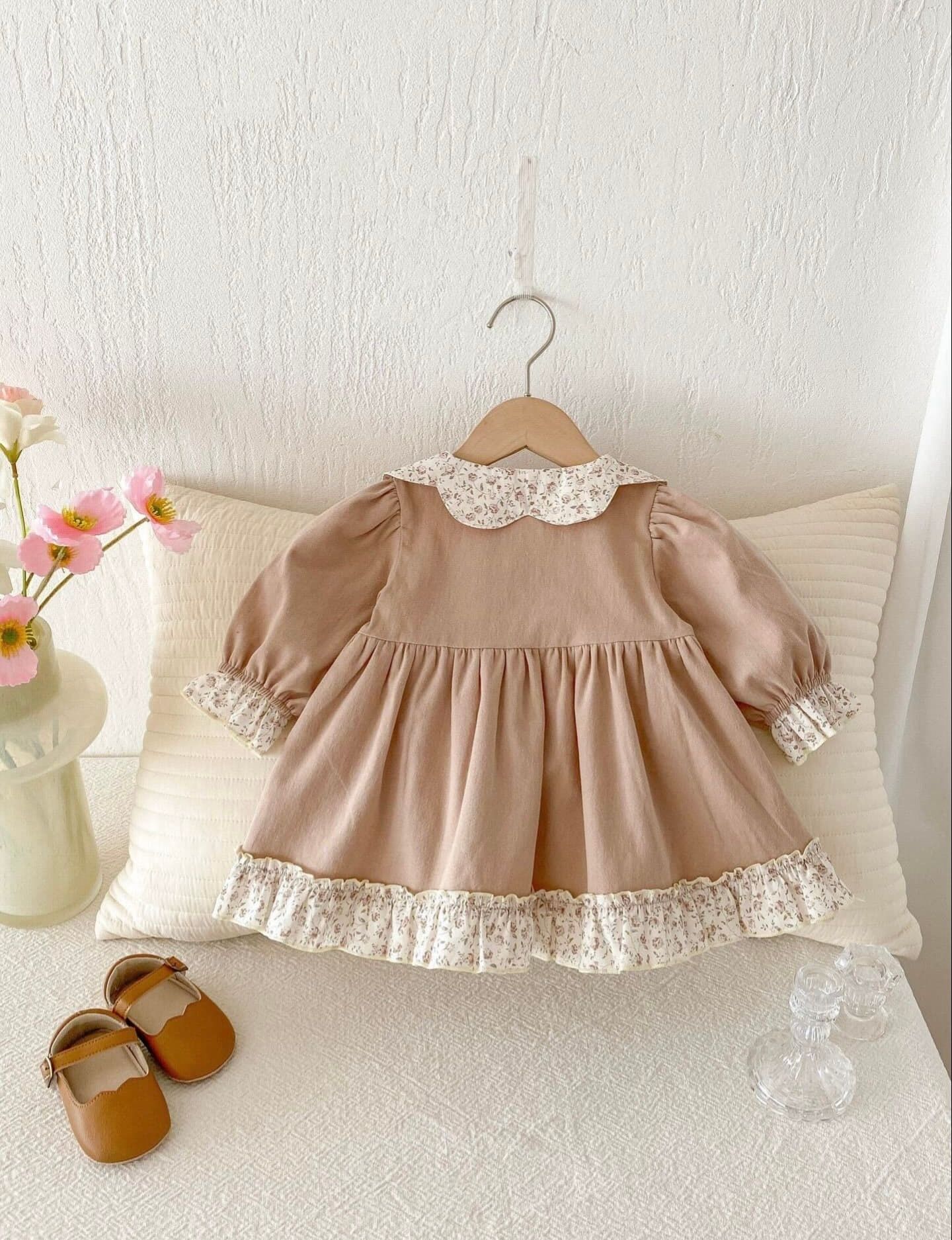 Beige ruffled dress or skirt layered with delicate lace trim and beige collar details against a white backdrop.