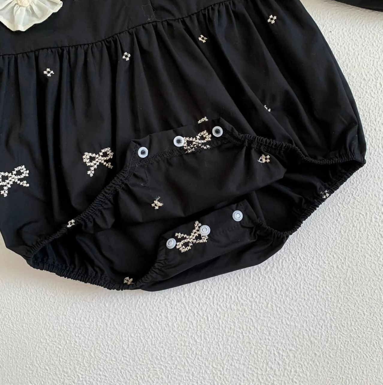 Black bloomers with delicate embroidered bow designs and small dots scattered across the fabric.