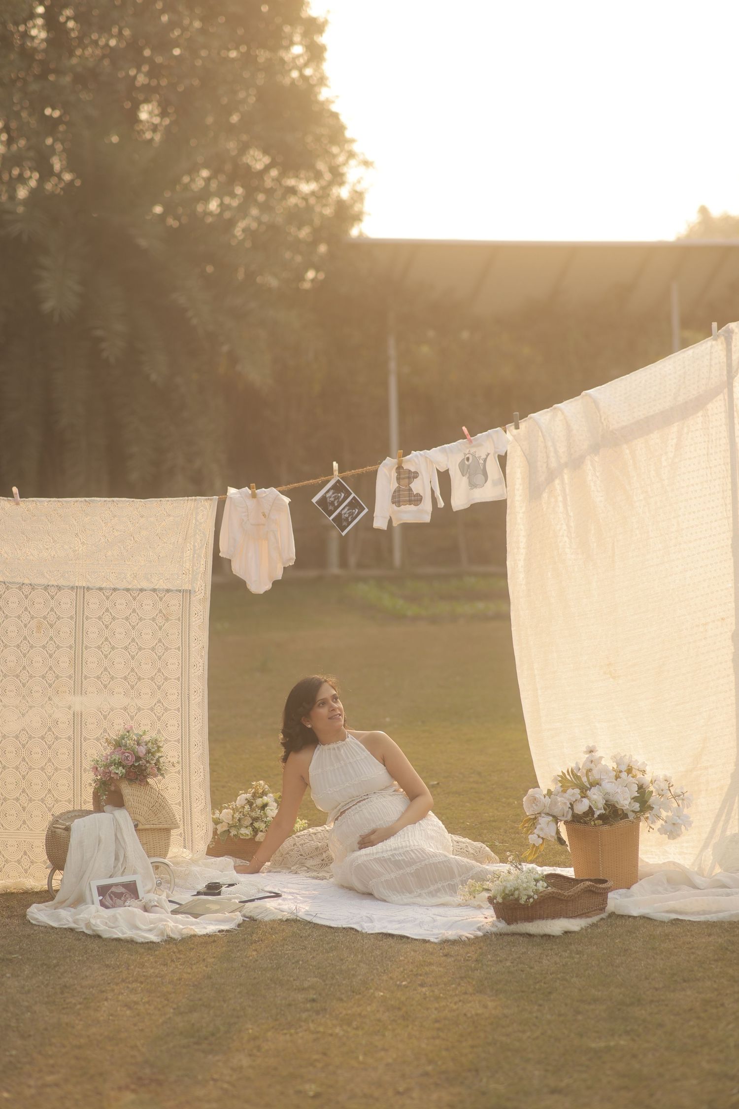 A series of white sheets hanging on clotheslines in a sunlit field creates a dreamy vintage laundry scene at sunset.