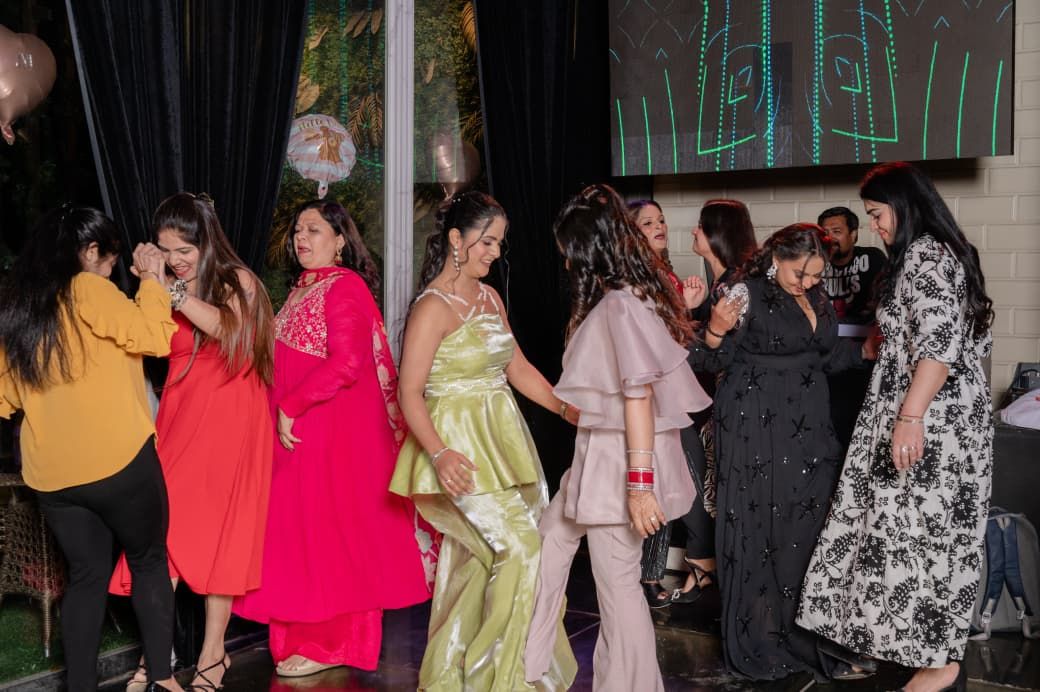 Women in colorful formal dresses dancing and socializing at an elegant evening party event.