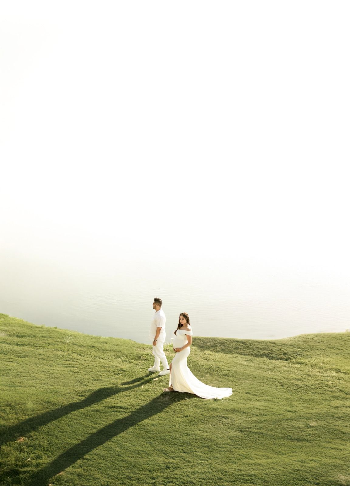Wedding couple on rolling green hillside during sunset.