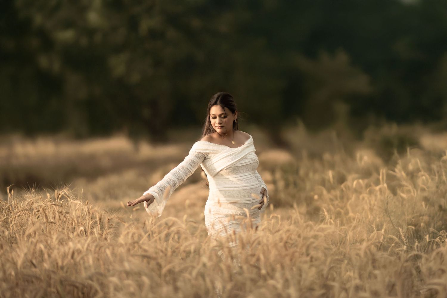 Person in white dress posing gracefully in golden wheat field at sunset.