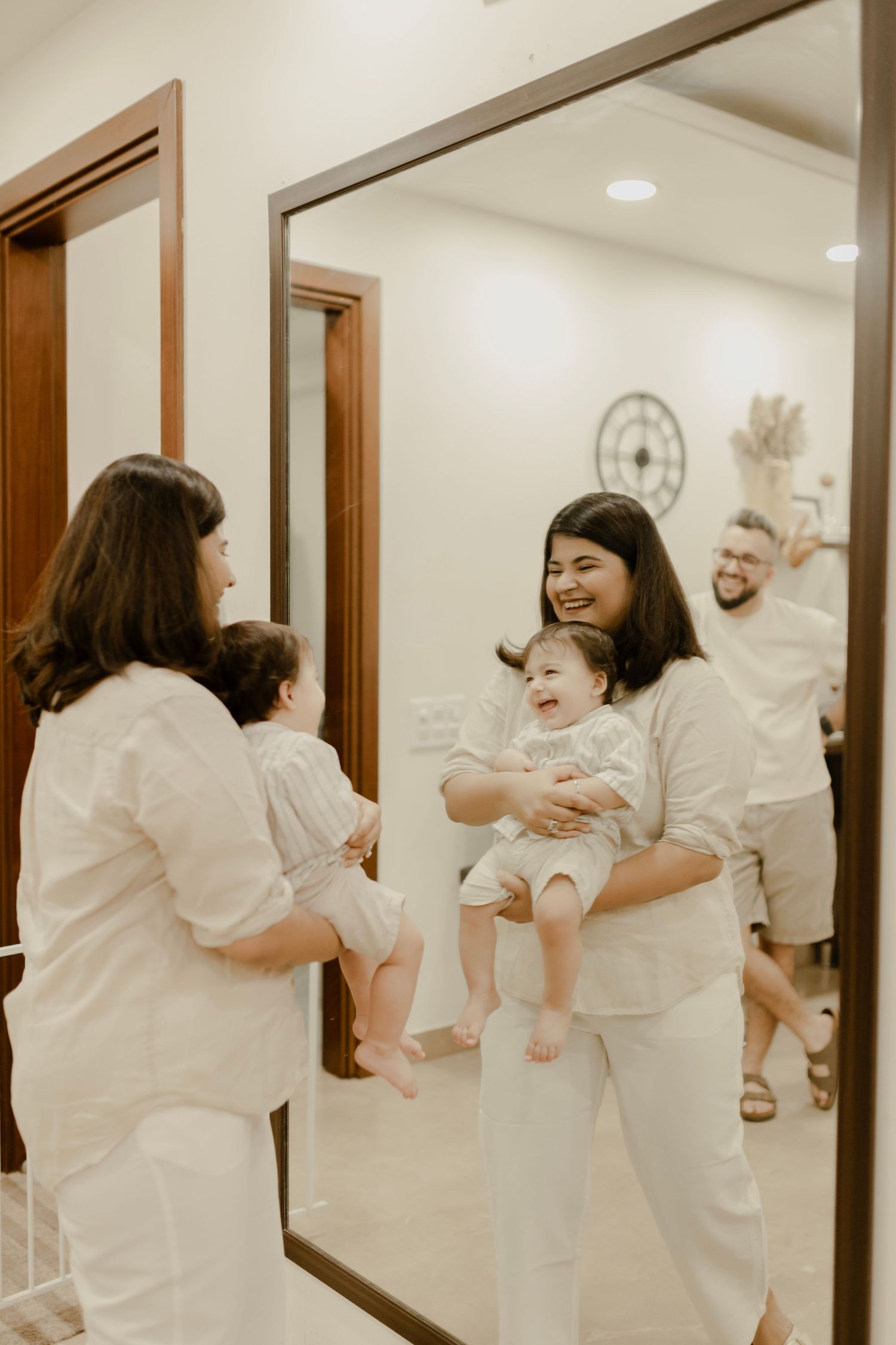 A sequence of four mirrored images showing people in white outfits embracing in a hallway.