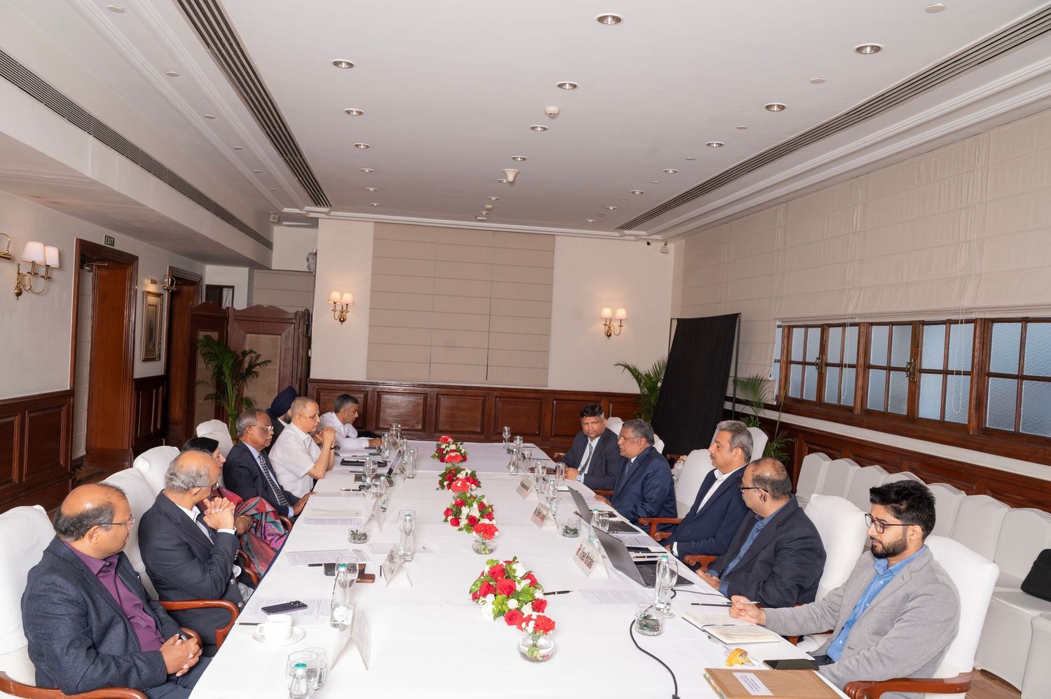 Business professionals seated around a large conference table during a formal meeting in an elegant boardroom.