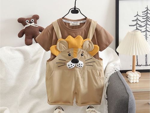 Cute children's outfit with brown t-shirt and beige overalls featuring a cartoon lion face design and plush teddy bear.