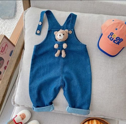 Adorable denim baby overalls with teddy bear applique shown with coral baseball cap and accessories.