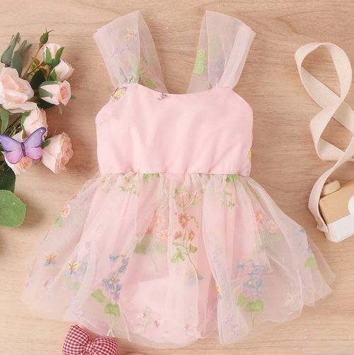 Delicate pink floral tulle dresses with ruffled details hanging on display.