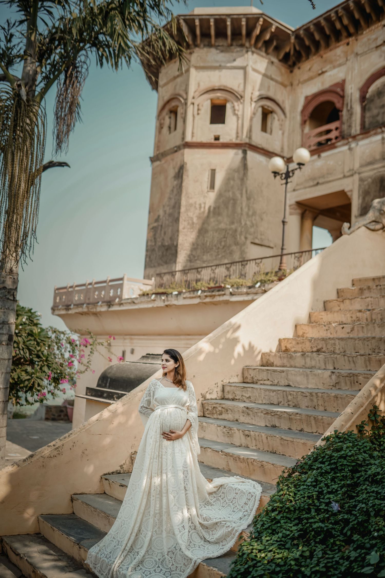 Maternity photography at historic building featuring flowing white lace dress on stone steps.