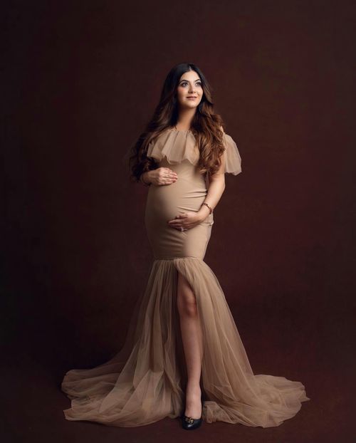 Moody maternity portraits in soft beige tones featuring an elegant flowing gown.