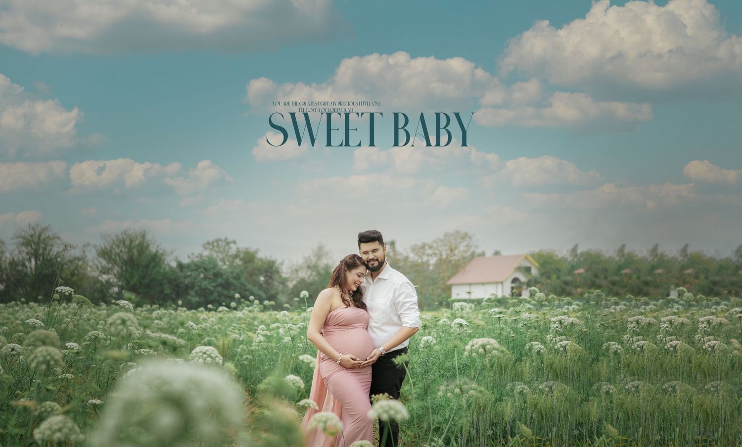 Romantic maternity photoshoot in a lush green meadow with wildflowers under blue summer skies.