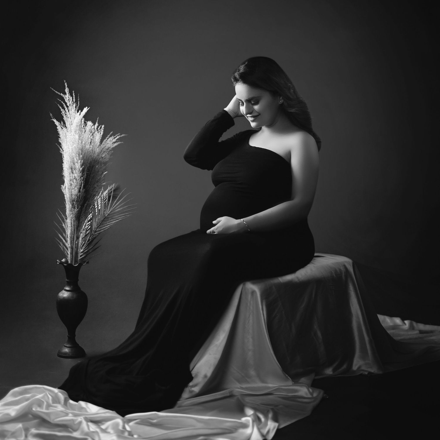Dramatic black and white maternity photos with feather decor and flowing fabric.