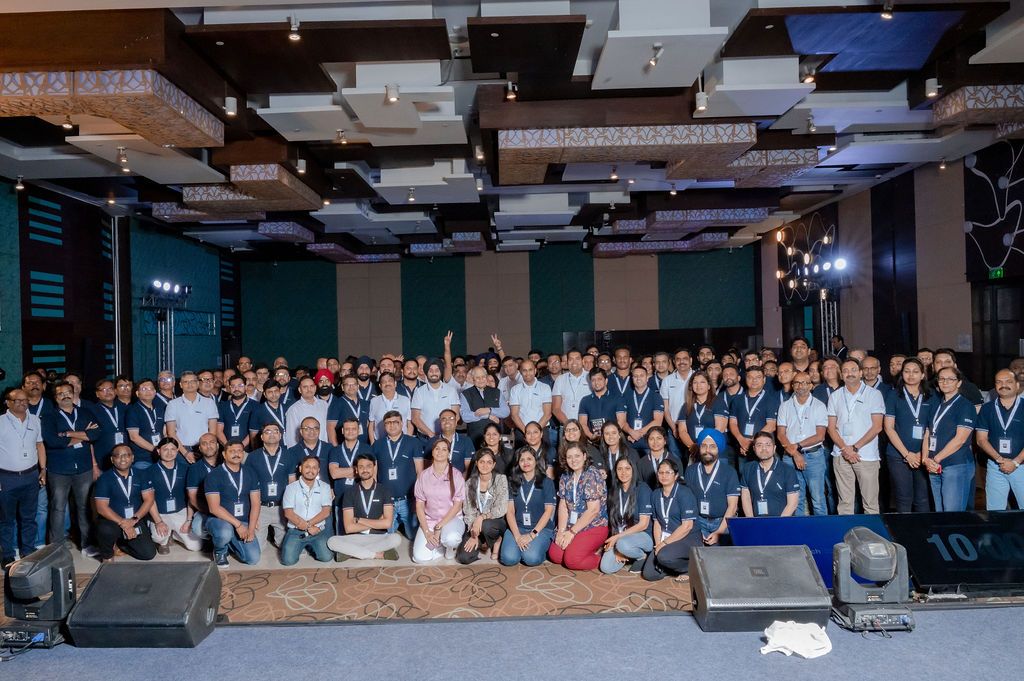 Large group of employees gathered in an office space for a company event or meeting.