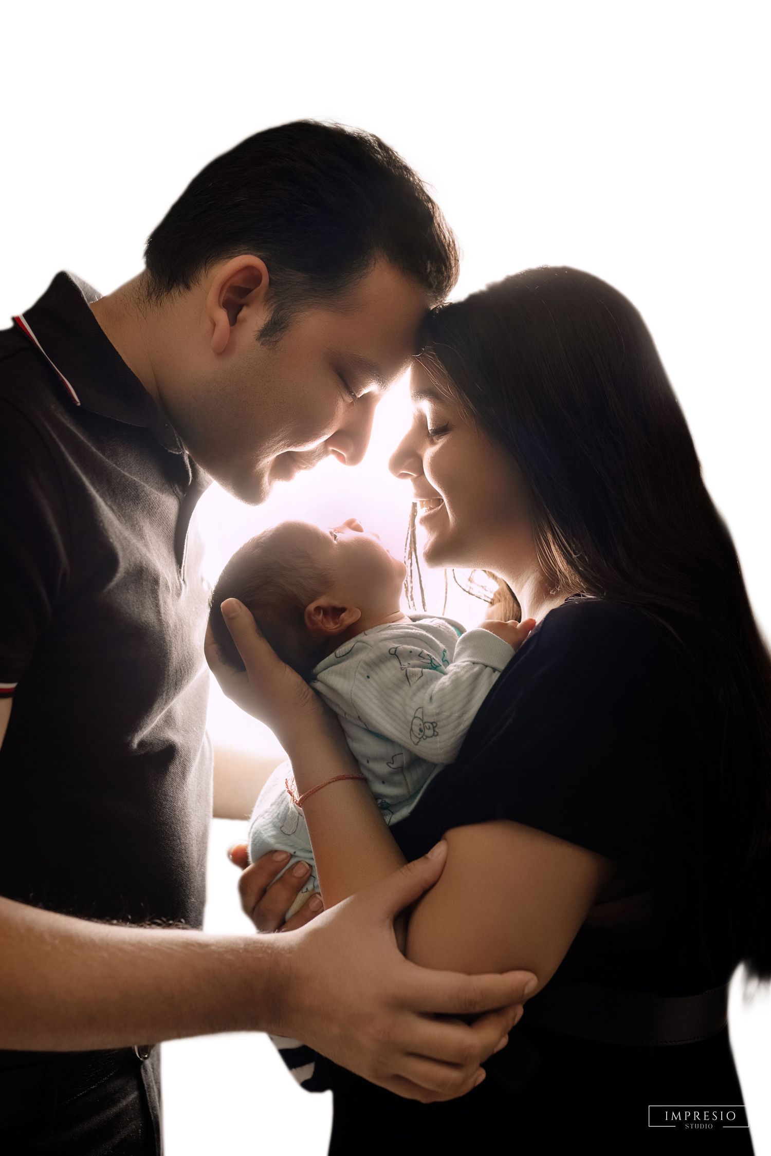Silhouette of parents tenderly holding their newborn baby, backlit with soft glowing light in an intimate family portrait.