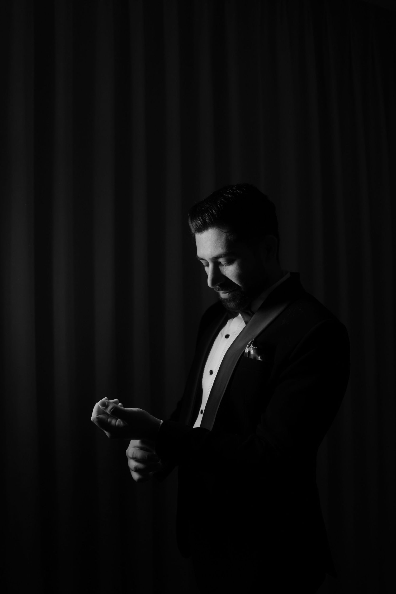 A dramatic black and white portrait series showing someone in formal attire checking their watch in silhouette.