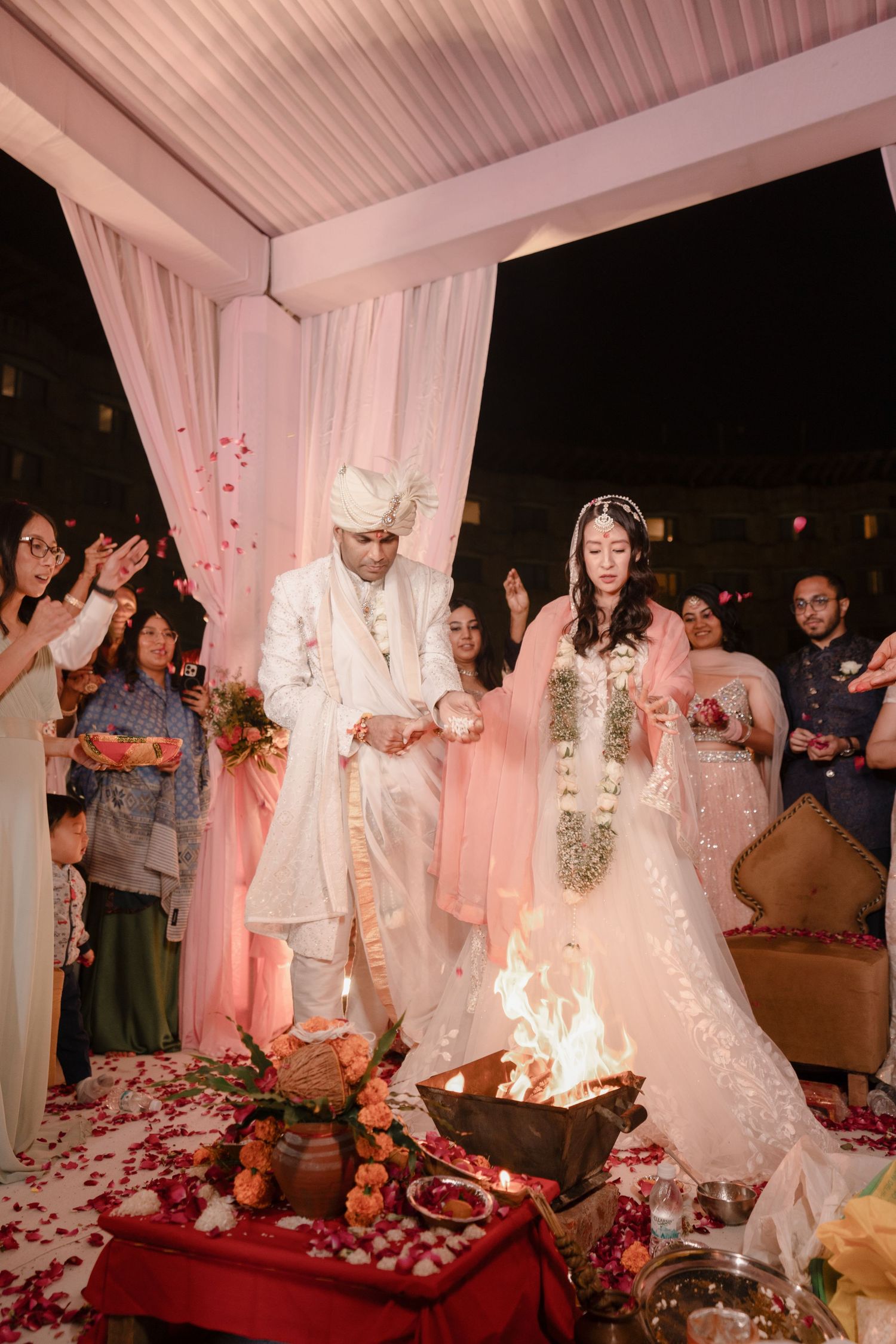 A wedding celebration sequence showing a couple during their ceremony with white drapes and rose petals decorating the venue.