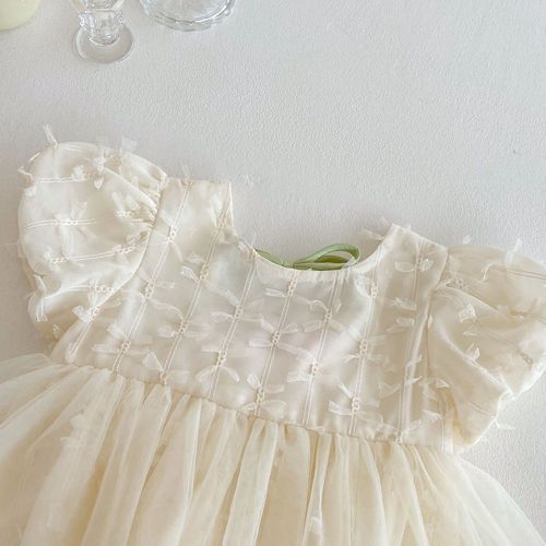 Row of dresses with ruffles and lace details hanging on display.