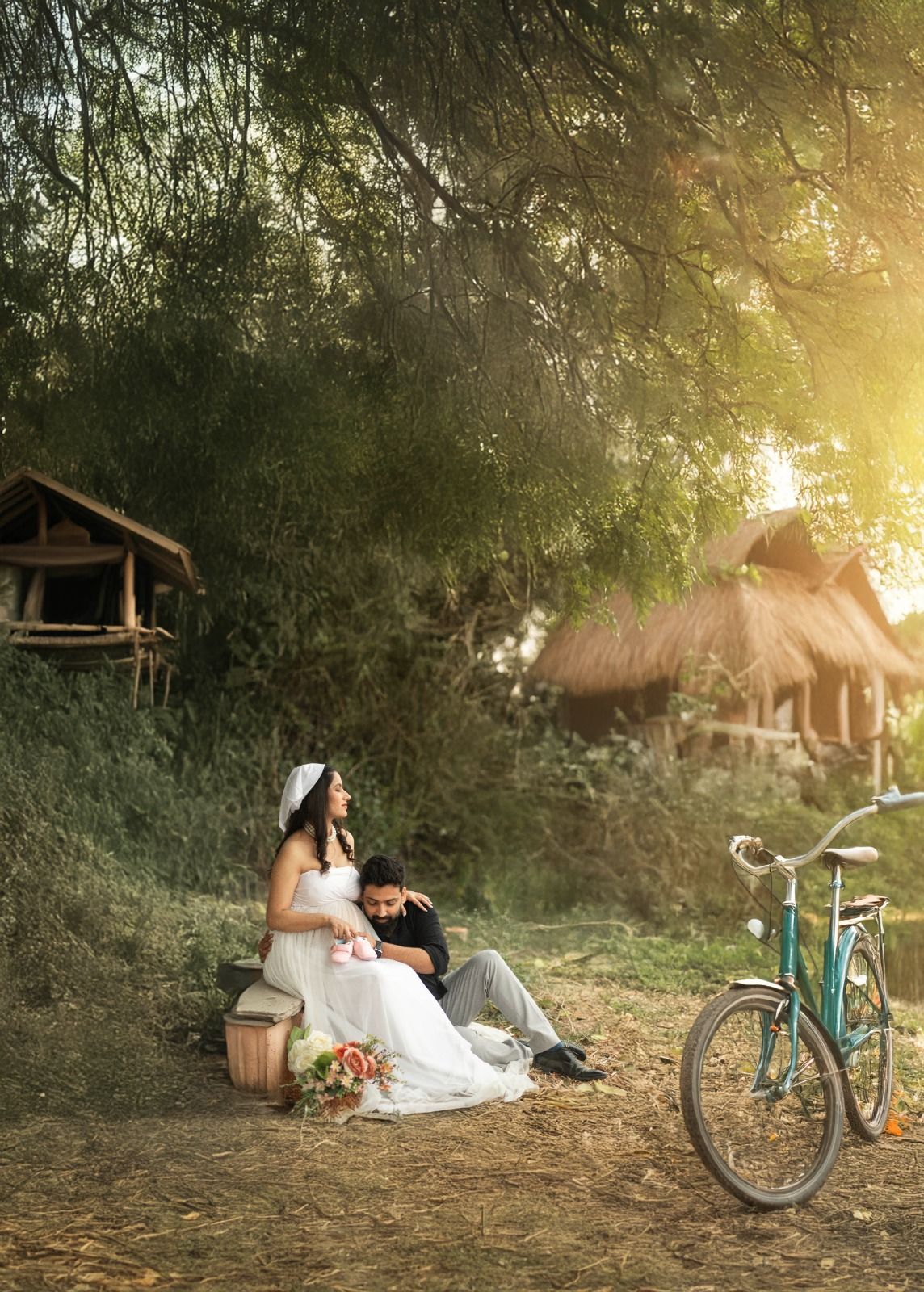 Whimsical outdoor scene with vintage bicycle, rustic cabin, and ethereal maternity dress at sunset.
