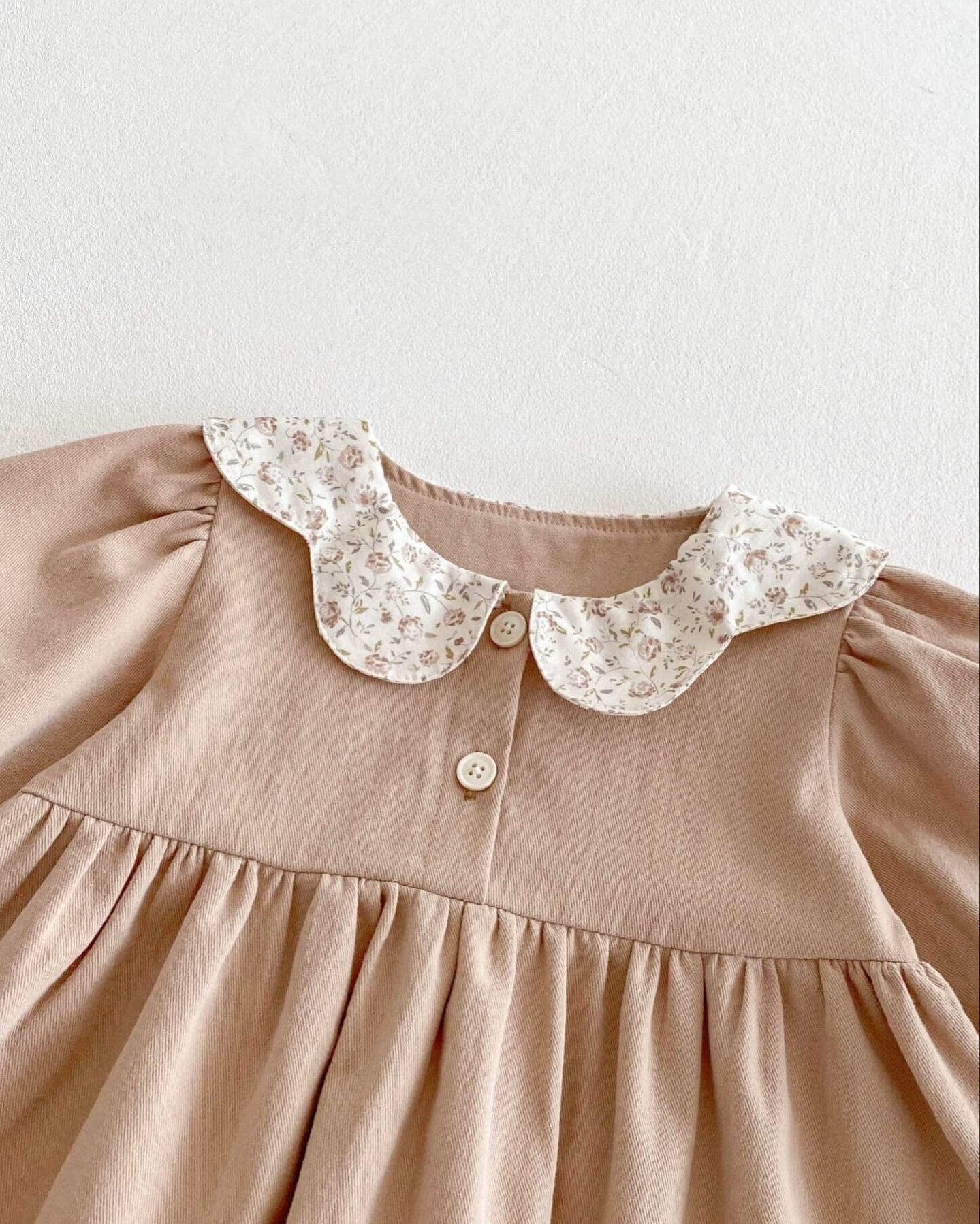 Peter Pan collar detail on a beige linen dress showing delicate white floral embroidered lace trim.