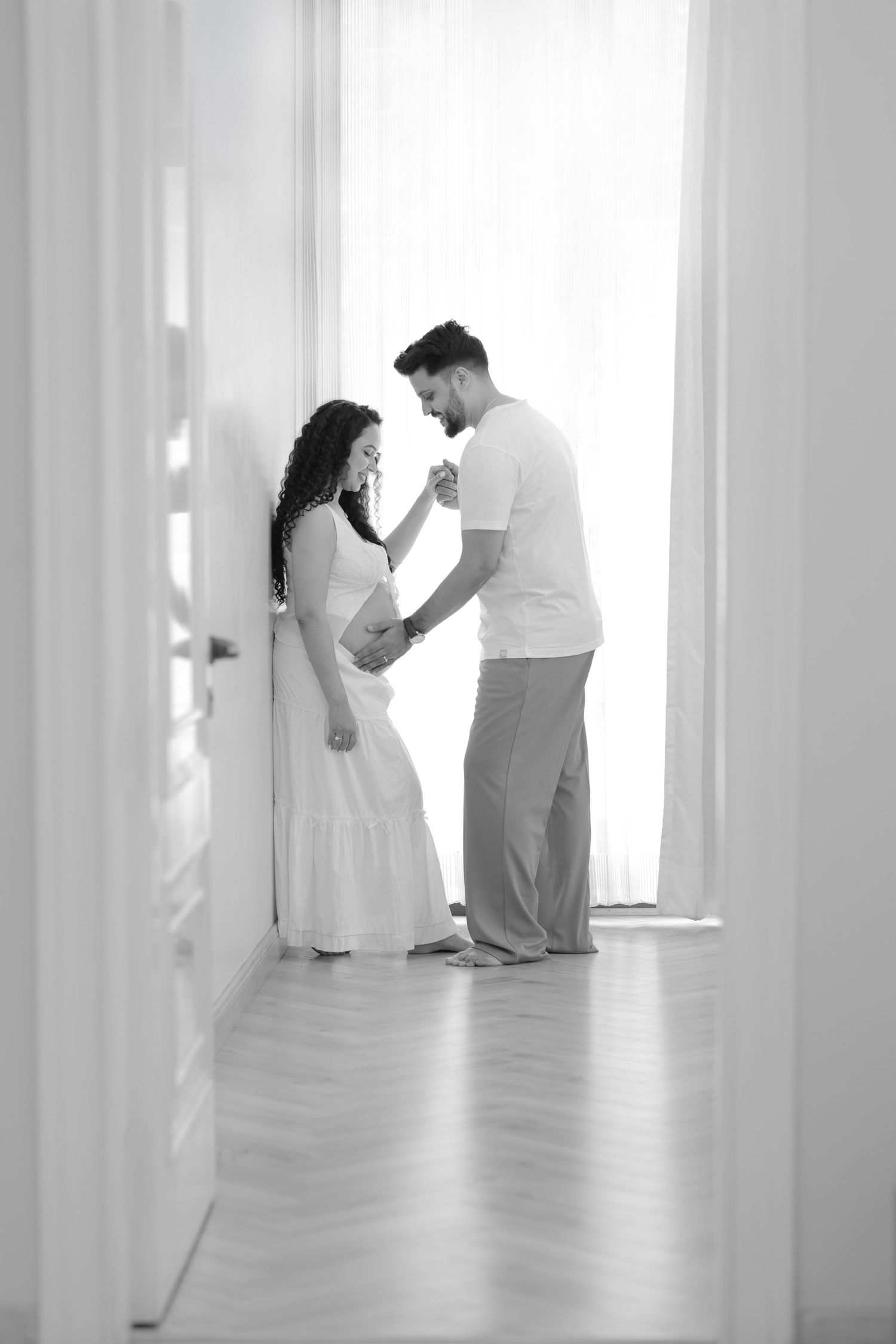 Black and white artistic photo of couple dancing together in a bright minimalist studio with white columns.
