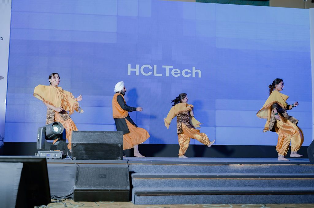 Performers in traditional Indian attire dance on stage at an HCLTech corporate event.