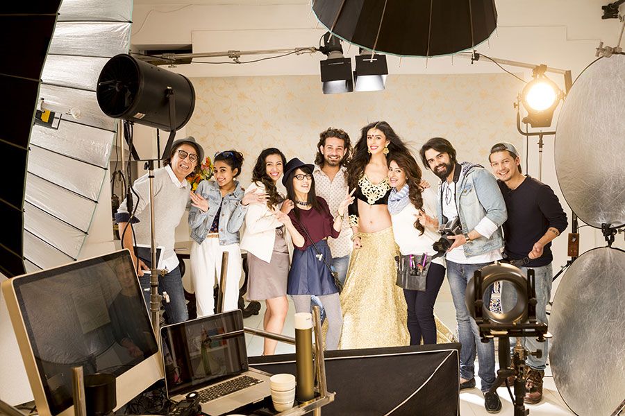 Group of people posing together on a professional photo shoot set with studio lighting equipment.