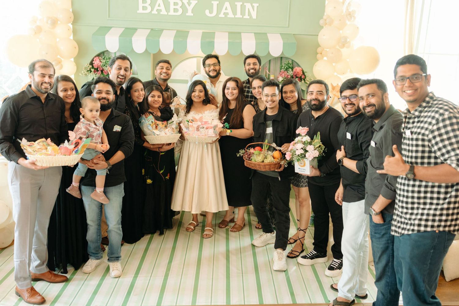 Group of friends celebrating a Baby Jain baby shower party, posing together with gifts and decorations.