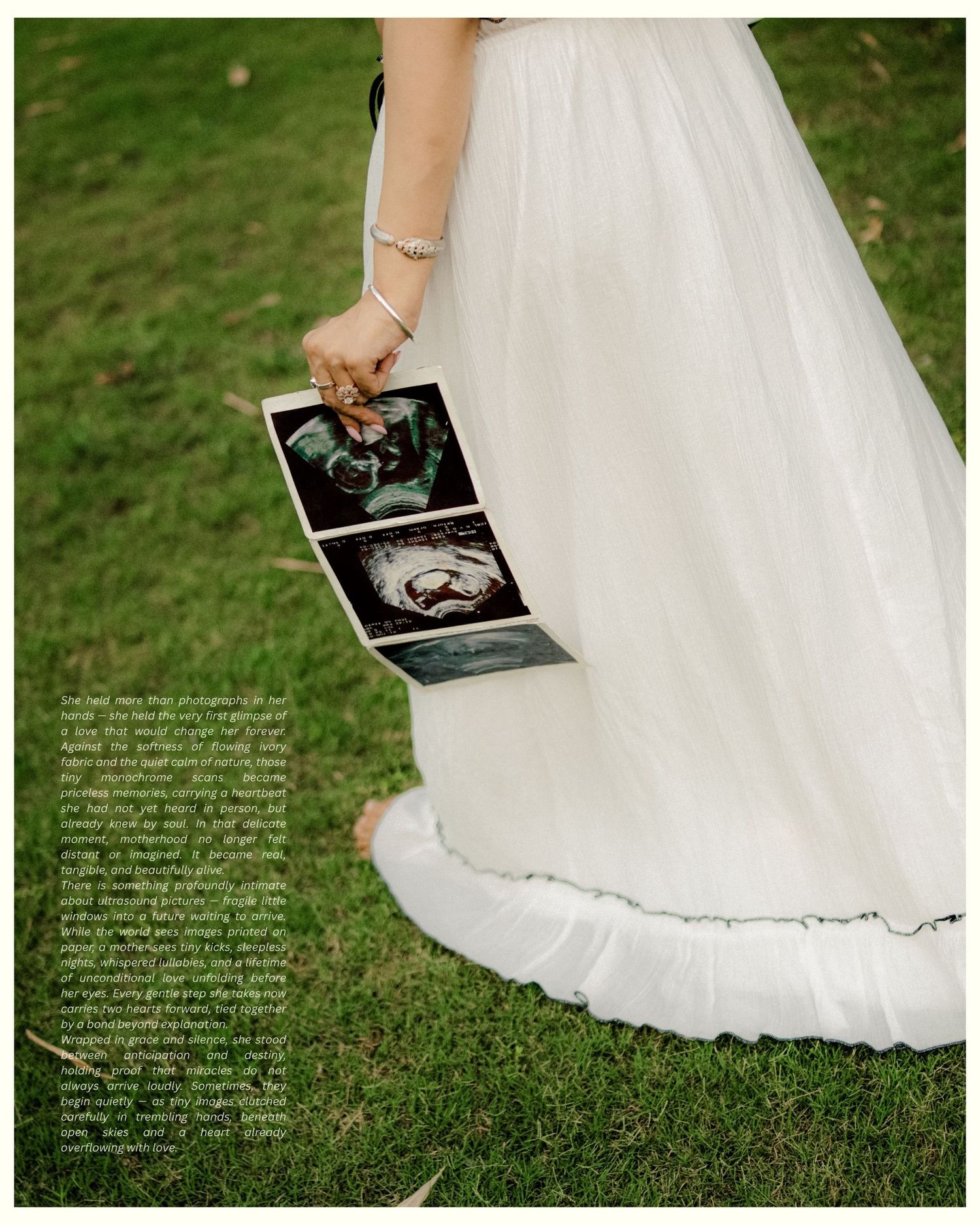 Bride in white gown holding ultrasound photos on green grass, announcing pregnancy on wedding day.