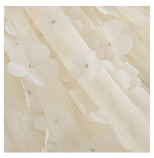 Ivory fabric detail showing delicate floral appliques and textured pattern.