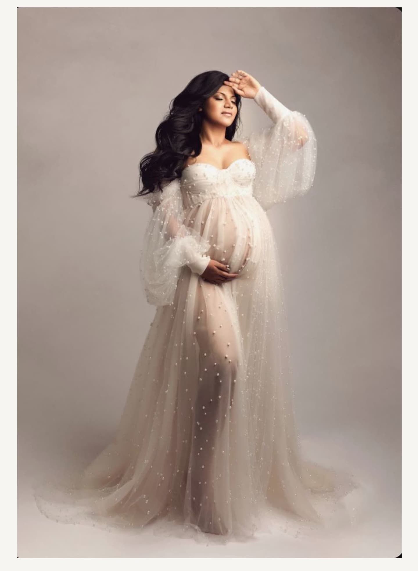 Elegant maternity photos featuring flowing tulle gown with sparkle details in studio setting.