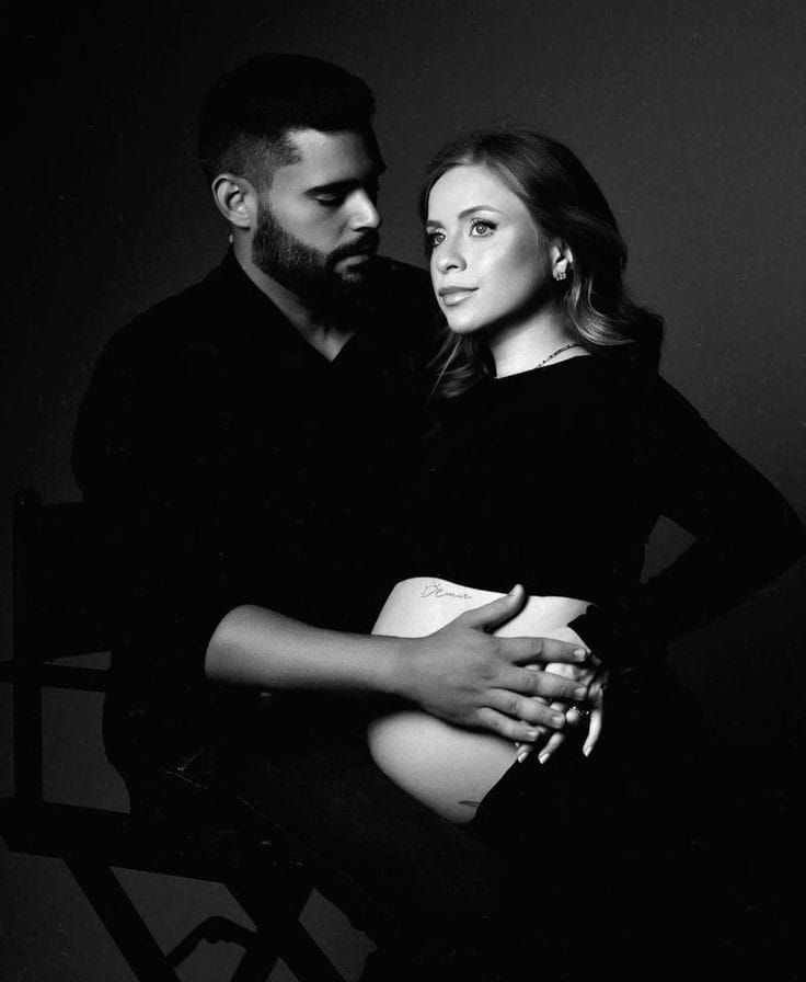 Intimate black and white couple's maternity portraits with moody lighting.