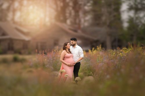 A romantic couple embraces during a golden hour sunset photoshoot in a dreamy outdoor meadow setting.