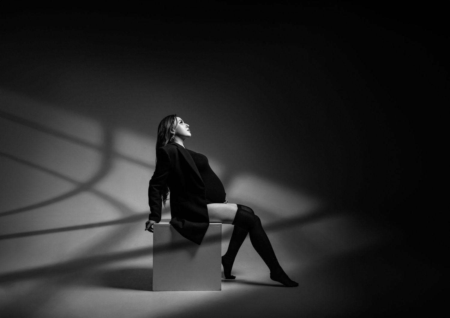 Dramatic black and white portrait with spotlight creating artistic shadows.