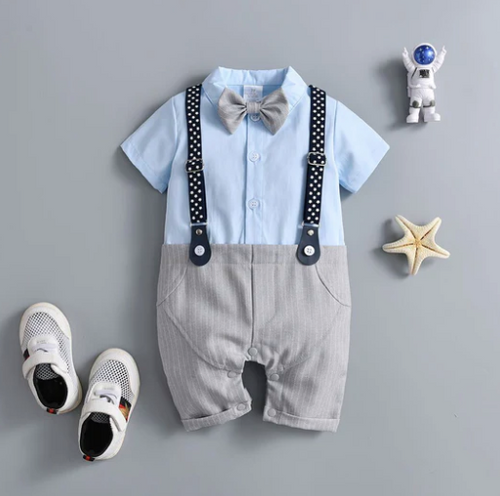 Formal baby romper with bow tie and polka dot suspenders styled with white shoes and accessories.