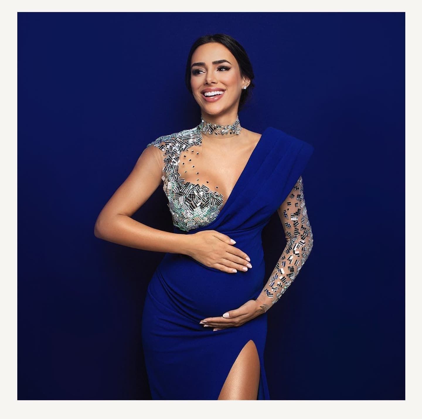 Elegant maternity portraits in royal blue dress with sparkling embellishments against navy background.
