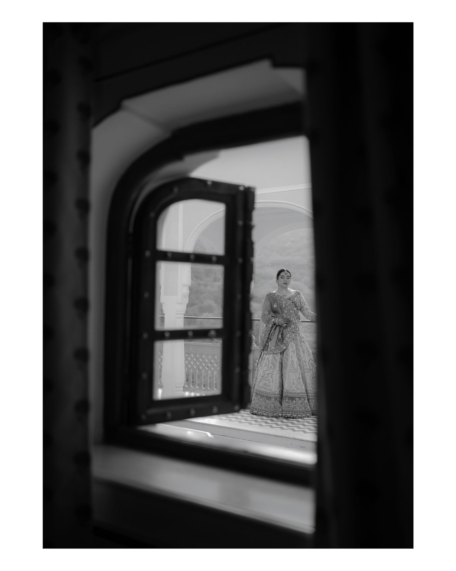Black and white photograph of a figure with crutches viewed through an arched window frame.