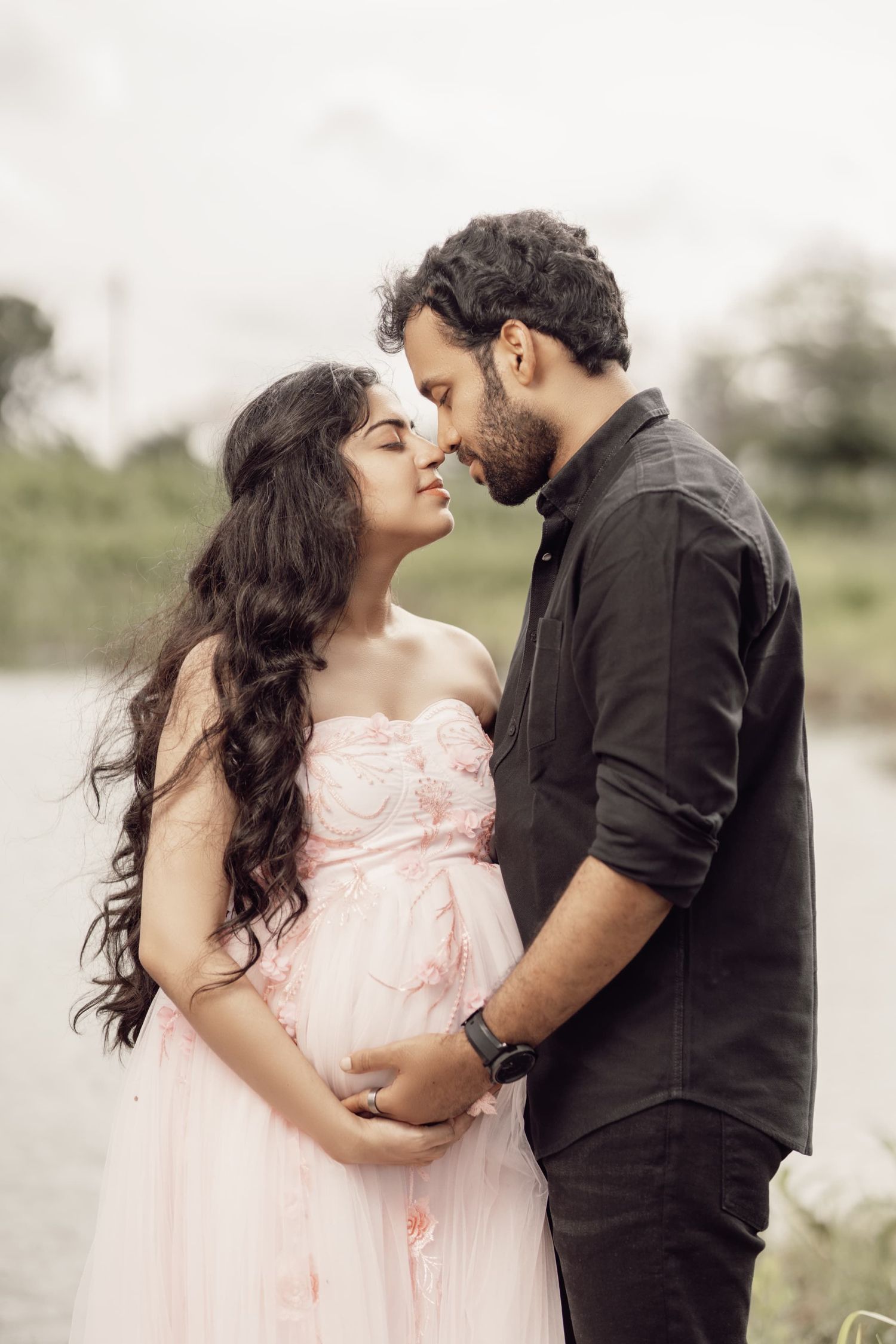 Romantic outdoor maternity photos with couple in pink dress and black shirt.