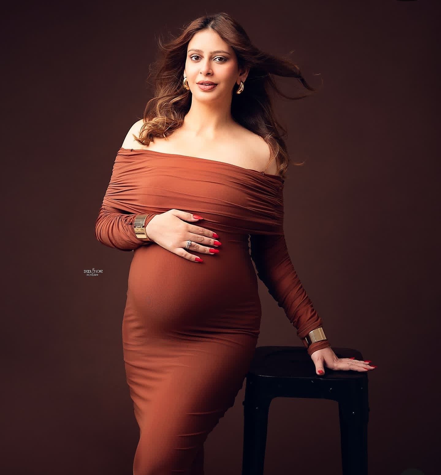 Professional maternity portraits in warm tones with off-shoulder rust dress and studio lighting.