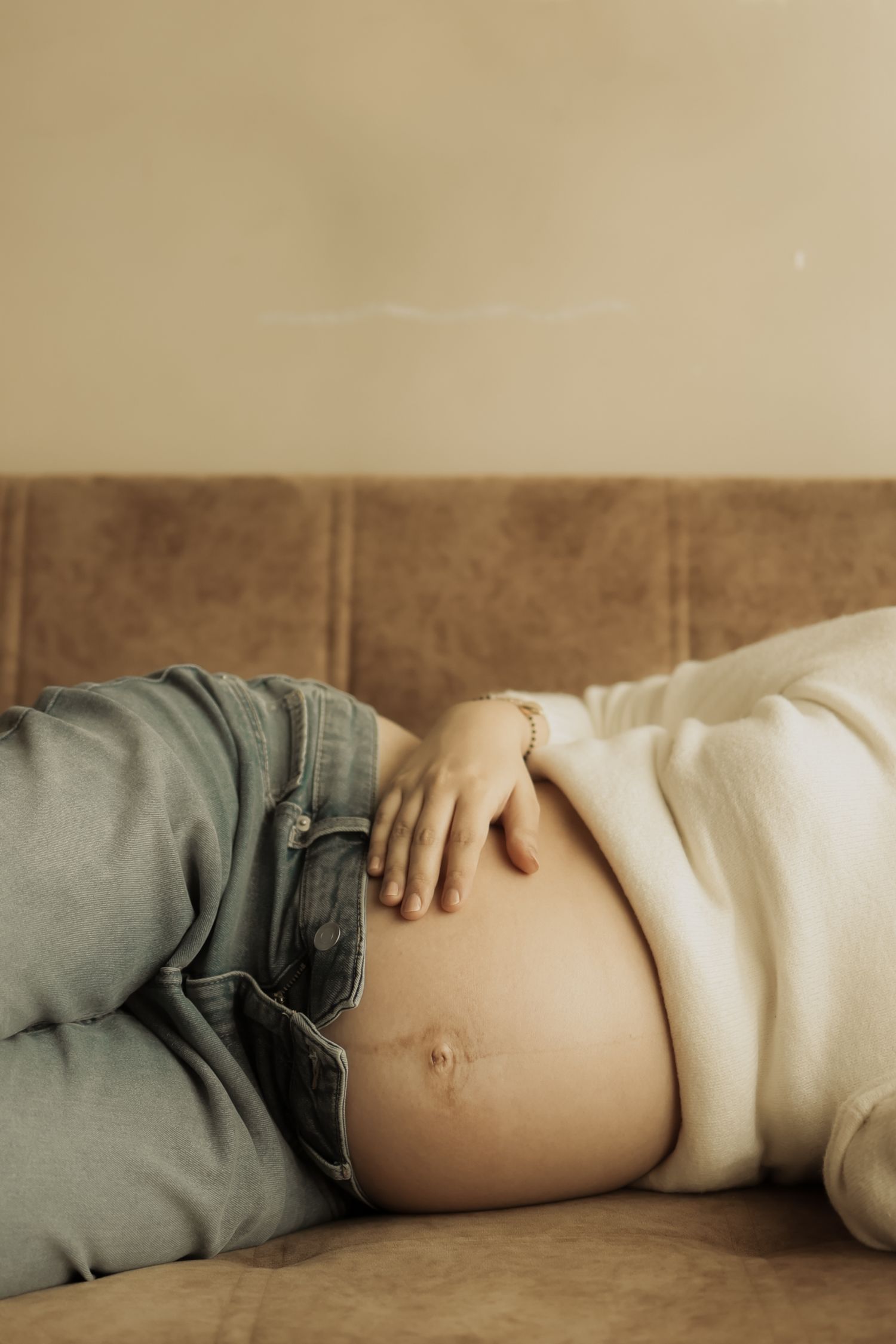 A series of connected photos showing a pregnant woman's belly in profile against a neutral beige background.