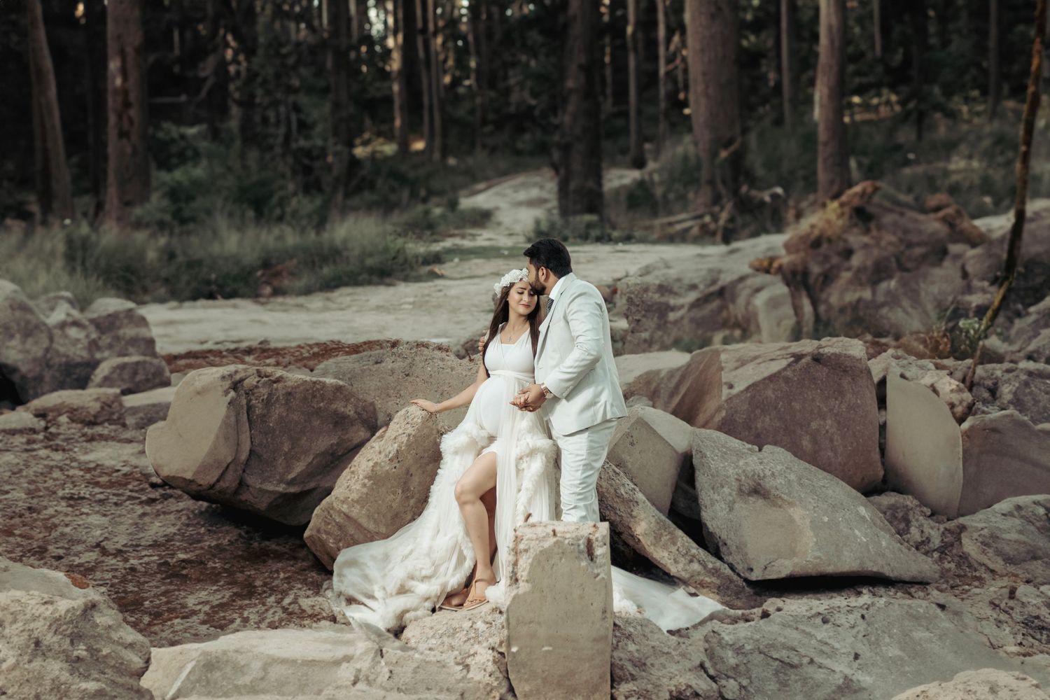Outdoor maternity photos on rocky terrain in a flowy white dress.