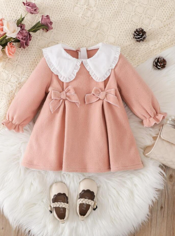 Pink baby dress with white peter pan collar and decorative bows shown with brown shoes.