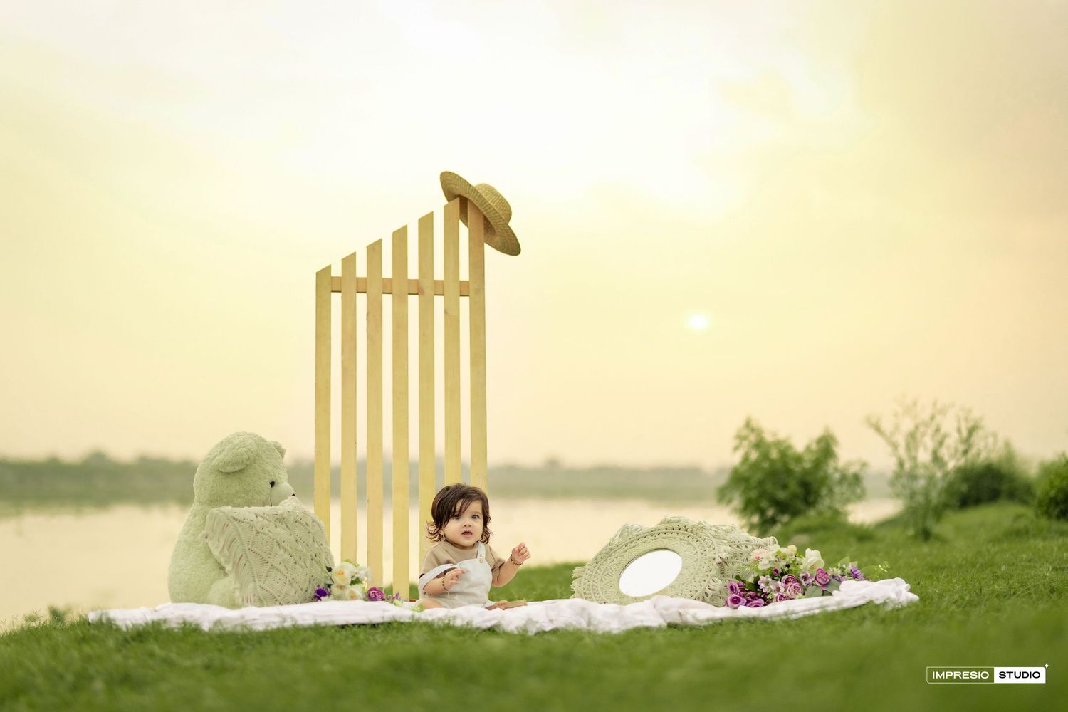 A dreamy outdoor scene with small toys and a decorative white fence gate against a soft golden background.