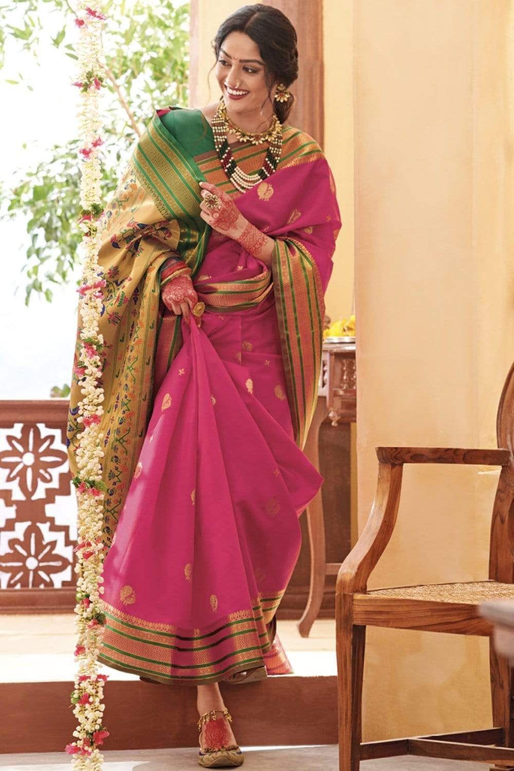 Vibrant pink and green silk saree with ornate gold border and traditional ethnic styling.