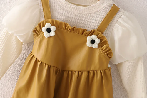 Mustard yellow pinafore dress with white puff sleeve top and flower details.