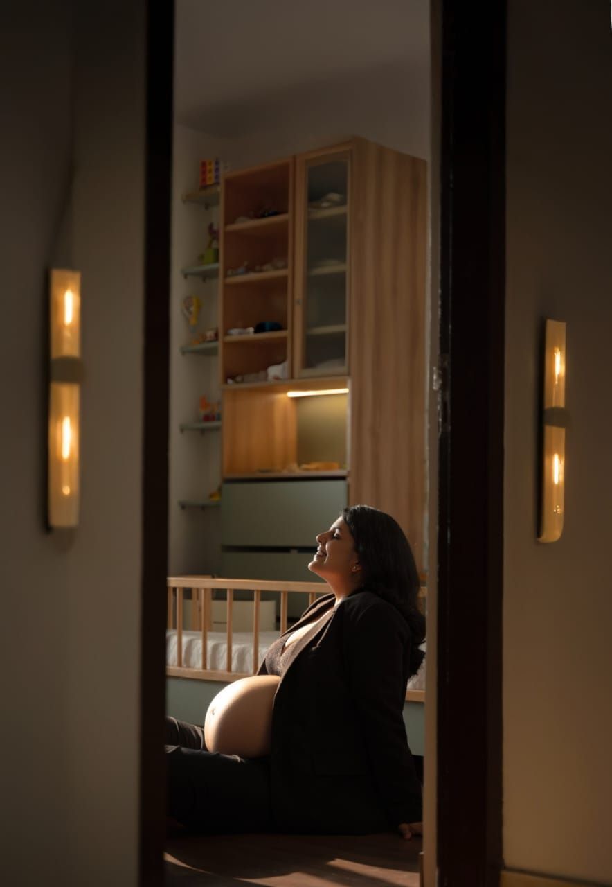 Silhouetted maternity portrait through doorway with warm ambient lighting.
