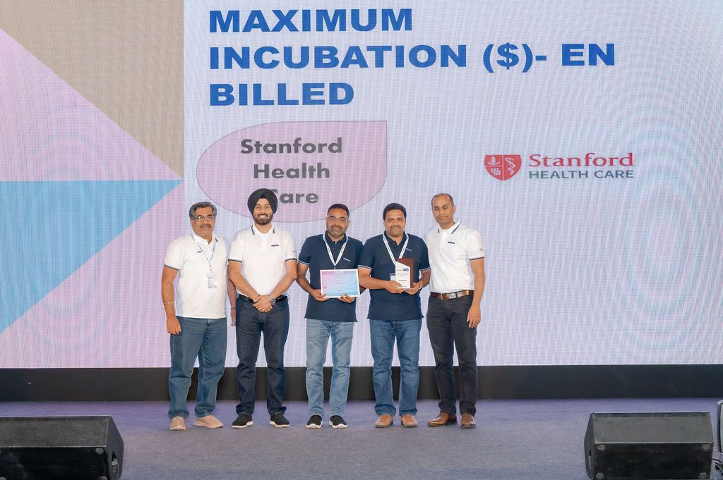 Group of professionals standing together on stage at a healthcare conference with Stanford Health banners displayed.