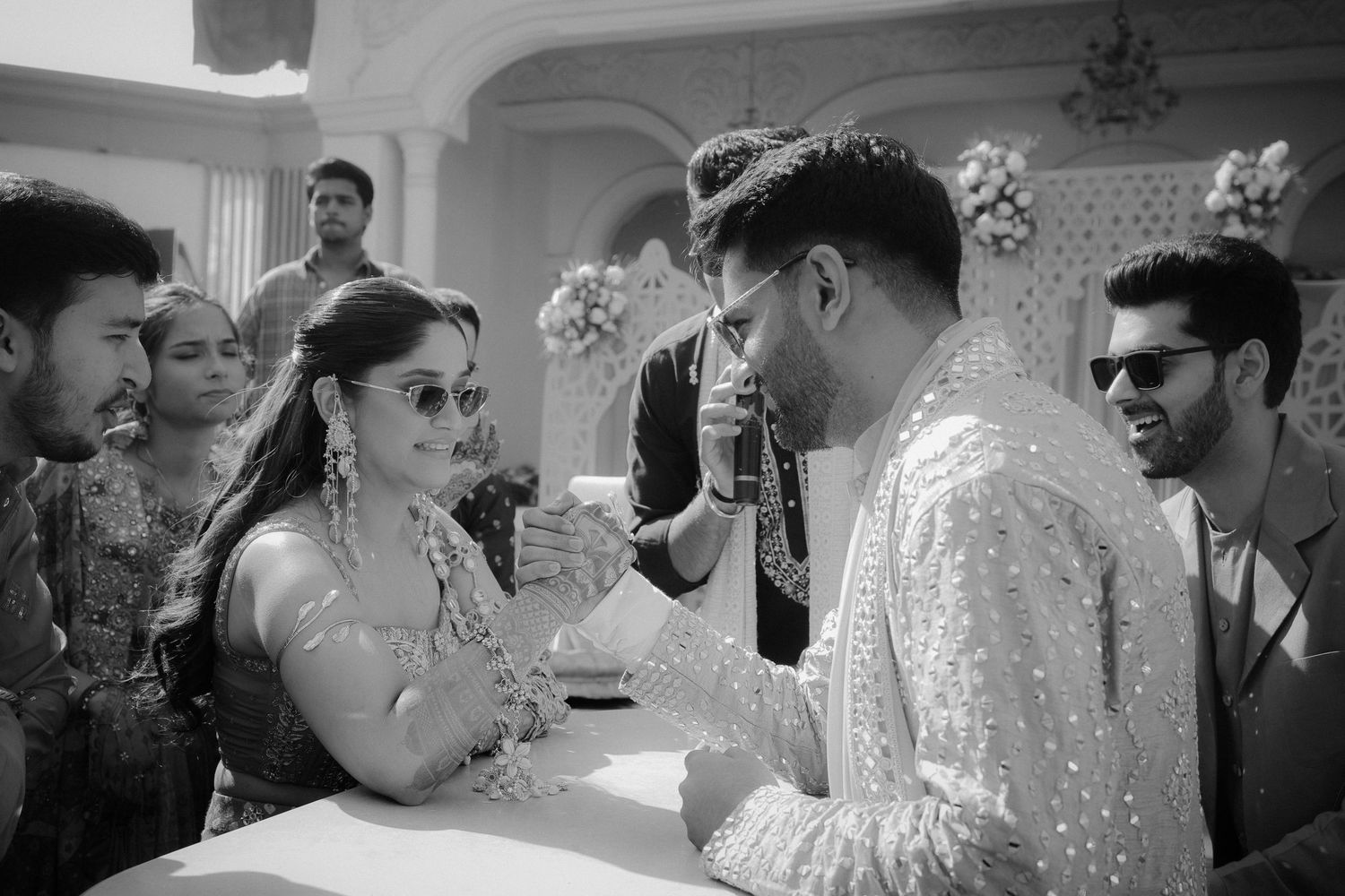 A series of black and white candid wedding reception photos showing guests interacting and celebrating together.