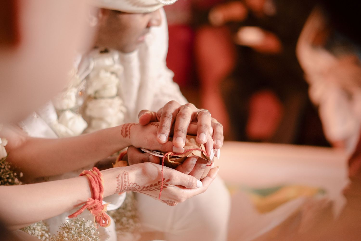 A sequence of hands working with white wedding cake frosting and decorative details in warm lighting.
