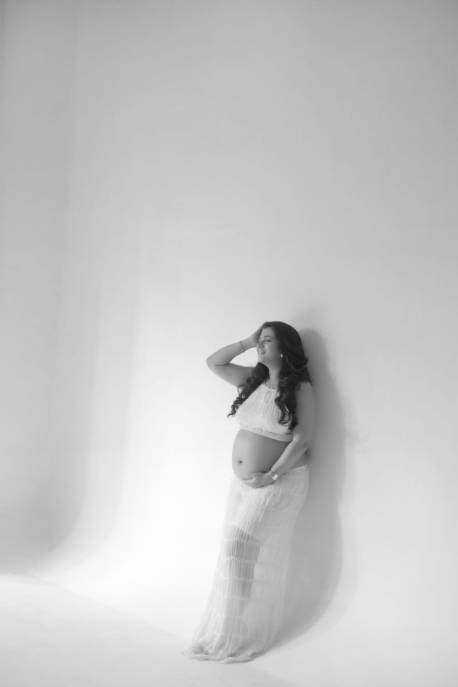 A series of minimalist black and white photographs showing a figure in flowing white fabric moving gracefully against a light background.