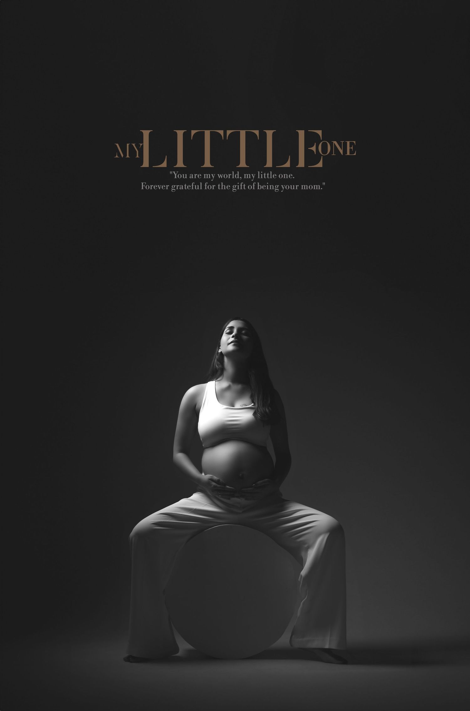 Black and white maternity photo of pregnant woman sitting, cradling belly, with My Little One text overlay.