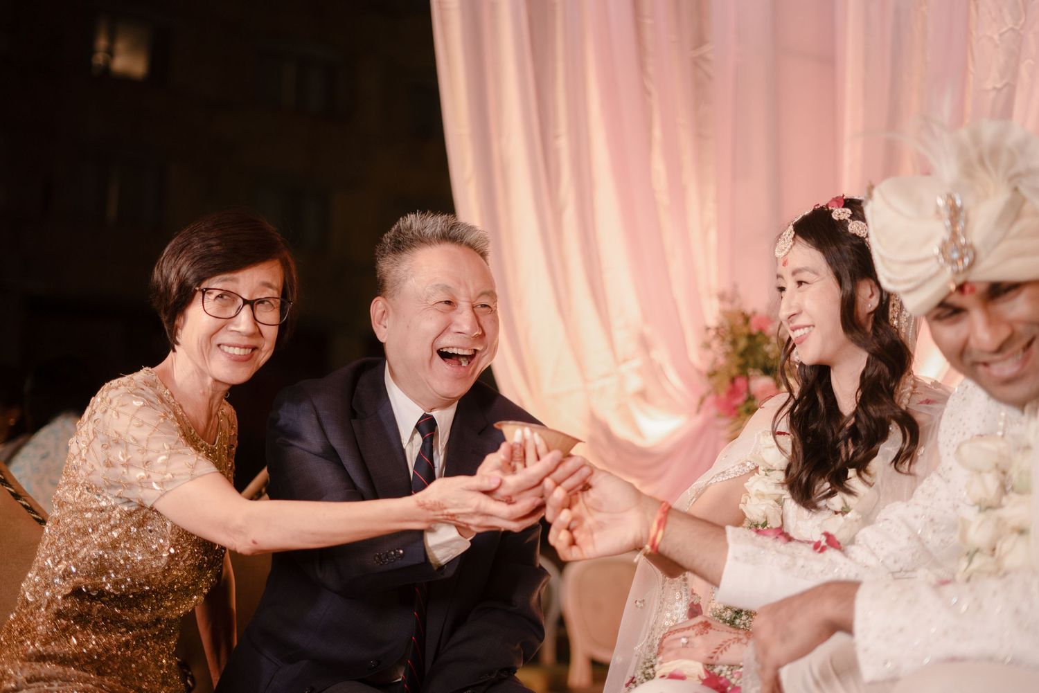 Wedding guests dance and celebrate together on a festive dance floor with pink lighting and decor.